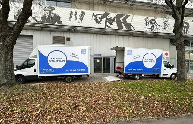 Zwei Umzugsfahrzeuge von Möbelmonteur stehen vor dem Firmengebäude beim Umzug Wien